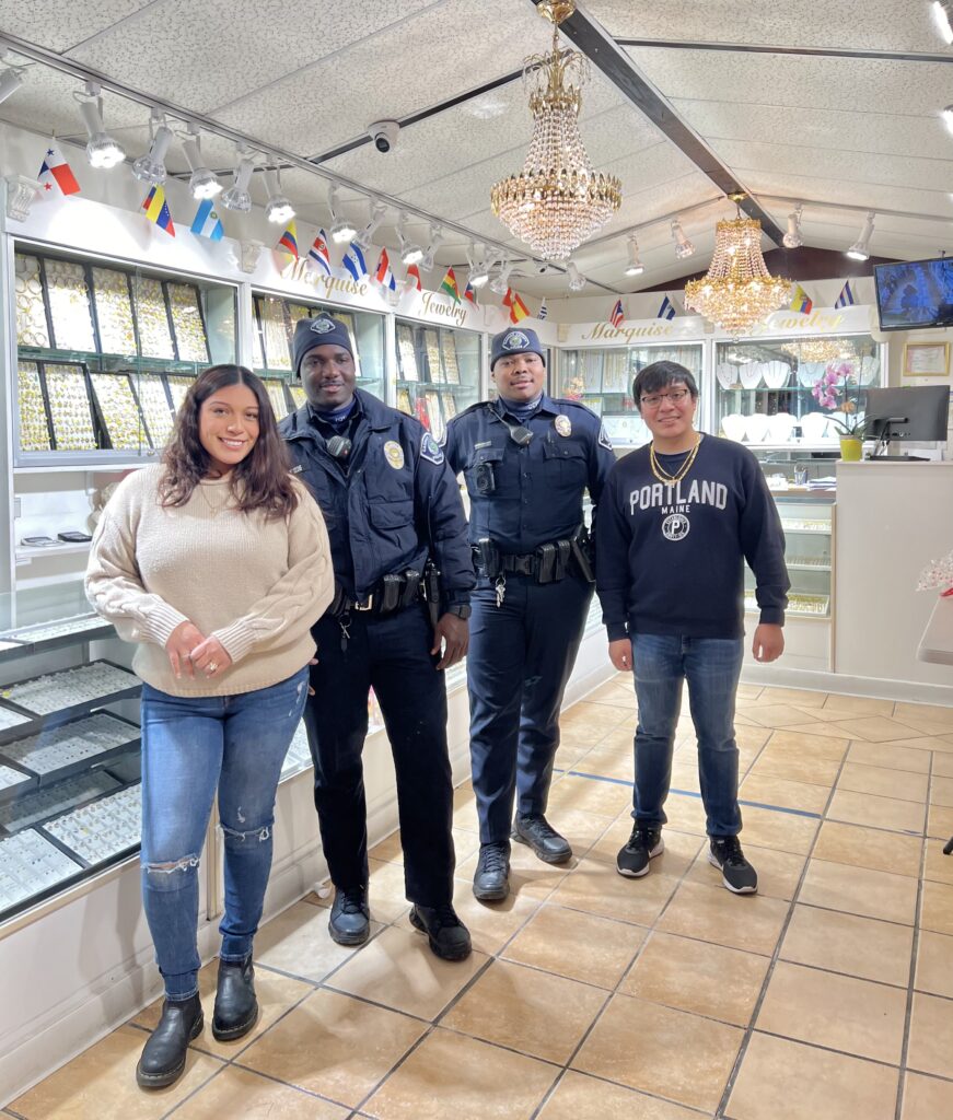Shop owner Sydney Paz, two Camden County police officers on a routine check, and owner Eladio Paz inside Marquise Jewelry in East Camden.